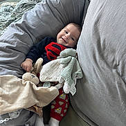 Emilio a rejoint le concours — aidez-le/la à gagner de superbes lots ! baby, superman_outfit, smile, pillow, blanket, stuffed_toy, couch, cozy, child, indoor, cute, red_pants, white_socks, soft_toys, sleeping_area, happy, person, infant, resting, comfort
