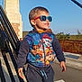 Louis a rejoint le concours — aidez-le/la à gagner de superbes lots ! child, toddler, boy, sunglasses, jacket, paw_patrol, pants, sneakers, outdoor, bridge, sunlight, smile, happy, standing, concrete, metal_railings, daytime, casual_clothing, cute, playful