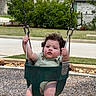 toddler, child, swing, playground, outdoor, park, curly_hair, green_swing, holding_chains, baby, grass, suburban, residential_area, daylight, casual_clothing, person, fun, recreation, seat, play