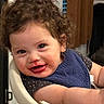Ezekiel is registered to the contest to win money with this photo: toddler, child, curly_hair, high_chair, bib, messy_face, food_stains, happy, smiling, indoor, person, cute, baby, playful, skin, arm, clothing, seat, face, expression