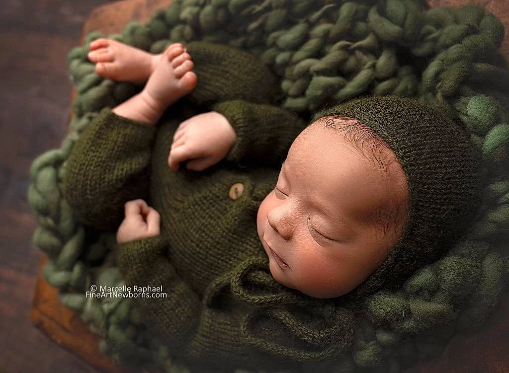 Everest is registered to the contest to win money with this photo: art, baby, baby_sleeping, baby_toddler_clothing, cheek, close_up, comfort, gesture, grass, grey, knit_cap, linens, pattern, person, skin, textile, thumb, toddler, vertebrate, wool