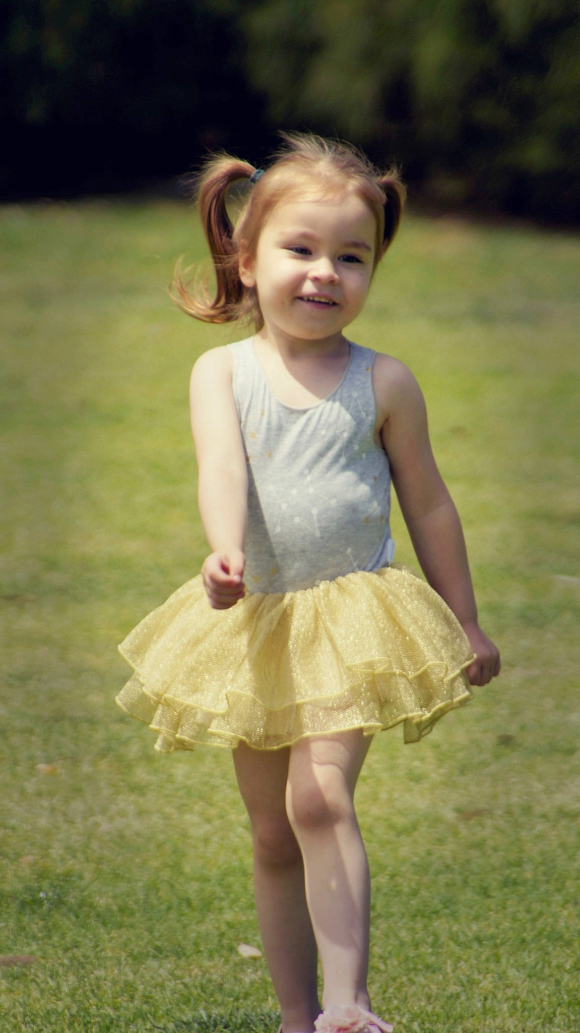 Olivia is registered to the contest to win money with this photo: ballet_tutu, child, child_model, clothing, costume, dance, dress, footwear, grass, person, pink, smile, toddler, yellow
