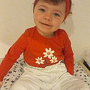 Anna a rejoint le concours — aidez-le/la à gagner de superbes lots ! child, toddler, smiling, headband, red_clothing, white_pants, sitting, indoor, face, person, cushion, patterned, stars, cute, happy, young_child, portrait, casual, baby, expression