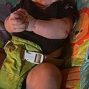 Alexis joined the competition — help win amazing prizes! baby, infant, child, seat, colorful, smile, hands, clasped, legs, black_shirt, green_seat, lion_print, cute, portrait, indoors, soft_lighting, happy, young_child, baby_toy, comfortable