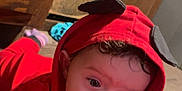 Alexis joined the competition — help win amazing prizes! baby, child, hoodie, red_clothing, crawling, floor, wooden_floor, cabinet, indoors, curly_hair, face, wide_eyes, person, infant, cute, exploring, playful, clothing, young_child, closeup