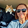 Girlie is registered to the contest to win money with this photo: woman, cat, sunglasses, car_interior, backpack, luggage, smile, tattoo, seatbelt, orange_cat, white_cat, short_hair, sunlight, road_trip, earbuds, casual_clothing, portrait, pet, travel, happy