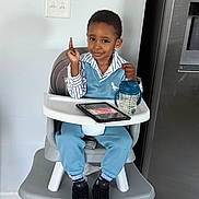 Elijah joined the competition — help win amazing prizes! toddler, high_chair, child, sippy_cup, tablet, blue_outfit, sneakers, smile, pointing, indoor, kitchen, floor, light_switch, modern_appliance, person, furniture, clothing, happy, seated, baby