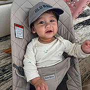 Dylan joined the competition — help win amazing prizes! baby, bouncer, cap, child, clothing, face, furniture, indoor, infant, laundry_basket, person, plush, portrait, reaching, seat, smile, soft_fabric, toy, young_child, babybjorn