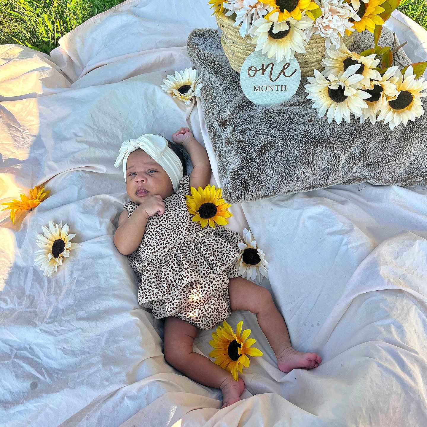 Zaryus is registered to the contest to win money with this photo: baby, basket, blanket, celebration, cute, feet, flower, grass, head, headband, infant, lying_down, milestone, nature, one_month, outdoor, patterned_clothing, skin, soft_texture, sunflower