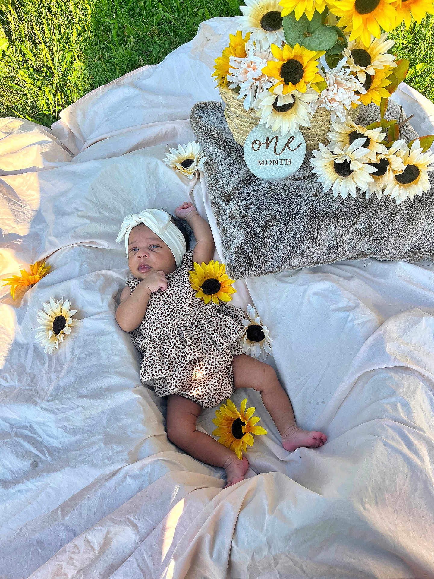 Zaryus is registered to the contest to win money with this photo: baby, infant, headband, blanket, sunflower, flower, basket, outdoor, grass, one_month, cute, patterned_clothing, lying_down, head, skin, feet, nature, celebration, soft_texture, milestone