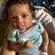 Jayla joined the competition — help win amazing prizes! baby, infant, child, curly_hair, tongue_out, onesie, rainbow, stars, fist, close_up, portrait, cute, playful, person, skin, expression, hand, indoor, holding, cozy