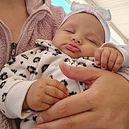 Ny'Ari joined the competition — help win amazing prizes! baby, infant, sleeping, portrait, close_up, face, bow, headband, blanket, leopard_print, clothing, mittens, hand, adult, parent, cradling, indoors, cozy, peaceful, family