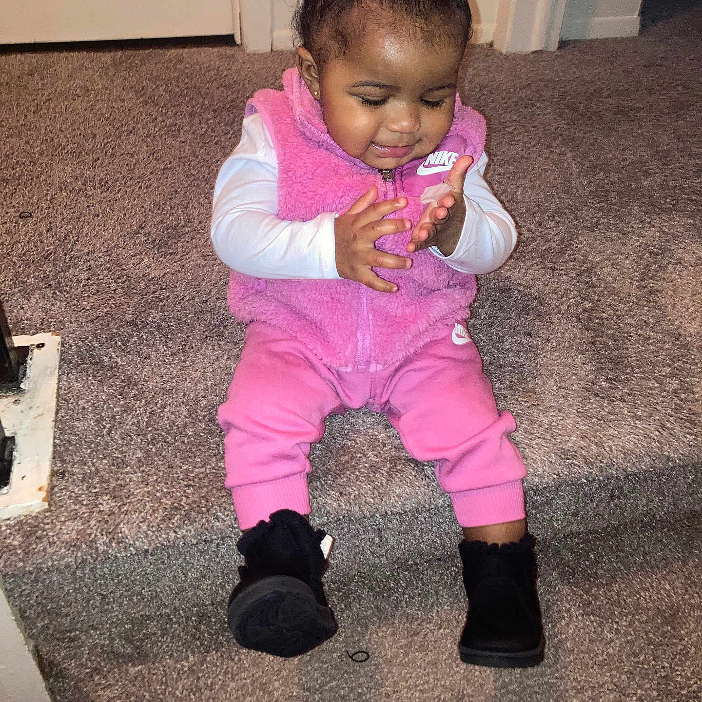 Sernity is registered to the contest to win money with this photo: toddler, child, baby, sitting, stairs, carpet, pink_clothing, nike, vest, pants, boots, hair_bow, indoor, happy, clapping, cute, person, smiling, young_child, fashion