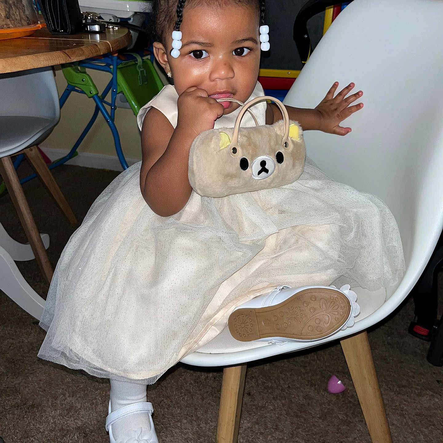 Sernity is registered to the contest to win money with this photo: toddler, child, dress, white_shoes, chair, indoor, plush_purse, cute, curly_hair, hair_bows, carpet, table, furniture, toy, small_handbag, person, smiling, sitting, young_child, curious