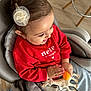 toddler, child, smiling, red_sweater, toy, giraffe_toy, hair_clip, high_chair, indoor, wooden_floor, happy, cute, baby, clothing, seat_belt, person, playful, hands, face, casual