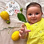 baby, blanket, button, child, cute, face, flower, fruit, green_leaf, hand, headband, indoor, infant, lemon, milestone_card, portrait, skin, smiling, soft_texture, yellow_clothing