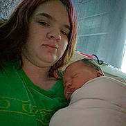 Charolette is registered to the contest to win money with this photo: woman, newborn, baby, sleeping, indoor, selfie, green_shirt, blanket, close_up, face, portrait, resting, mother_and_child, window, curtains, hair, person, cozy, family, intimate