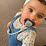 Arya a rejoint le concours — aidez-le/la à gagner de superbes lots ! baby, child, pacifier, headband, denim_overalls, floral_shirt, blue_eyes, indoor, carpet, cute, portrait, person, toddler, clothing, closeup, looking_up, skin, face, hand, foot
