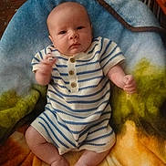 Michael joined the competition — help win amazing prizes! baby, infant, child, striped_clothing, romper, blanket, colorful_blanket, fuzzy_texture, sitting, indoors, cute, small_hands, bare_feet, wood_floor, furniture, curious, portrait, young_child, comfortable, warm
