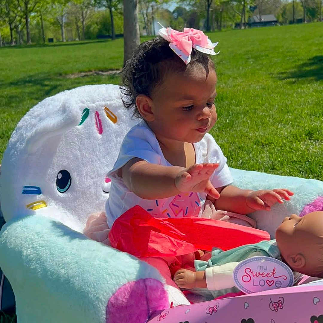 Xamira joined the competition — help win amazing prizes! toddler, child, doll, plush_chair, pink_bow, outdoor, grass, trees, sunny, blue_sky, toy, baby, cute, playing, pink, colorful, park, young_child, sitting, daytime