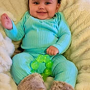 Cayla joined the competition — help win amazing prizes! baby, infant, smile, curly_hair, turquoise_clothing, fuzzy_boots, green_toy, blanket, cozy, indoors, happy, child, cute, soft_texture, portrait, sitting, warm, home, comfortable, teething_toy