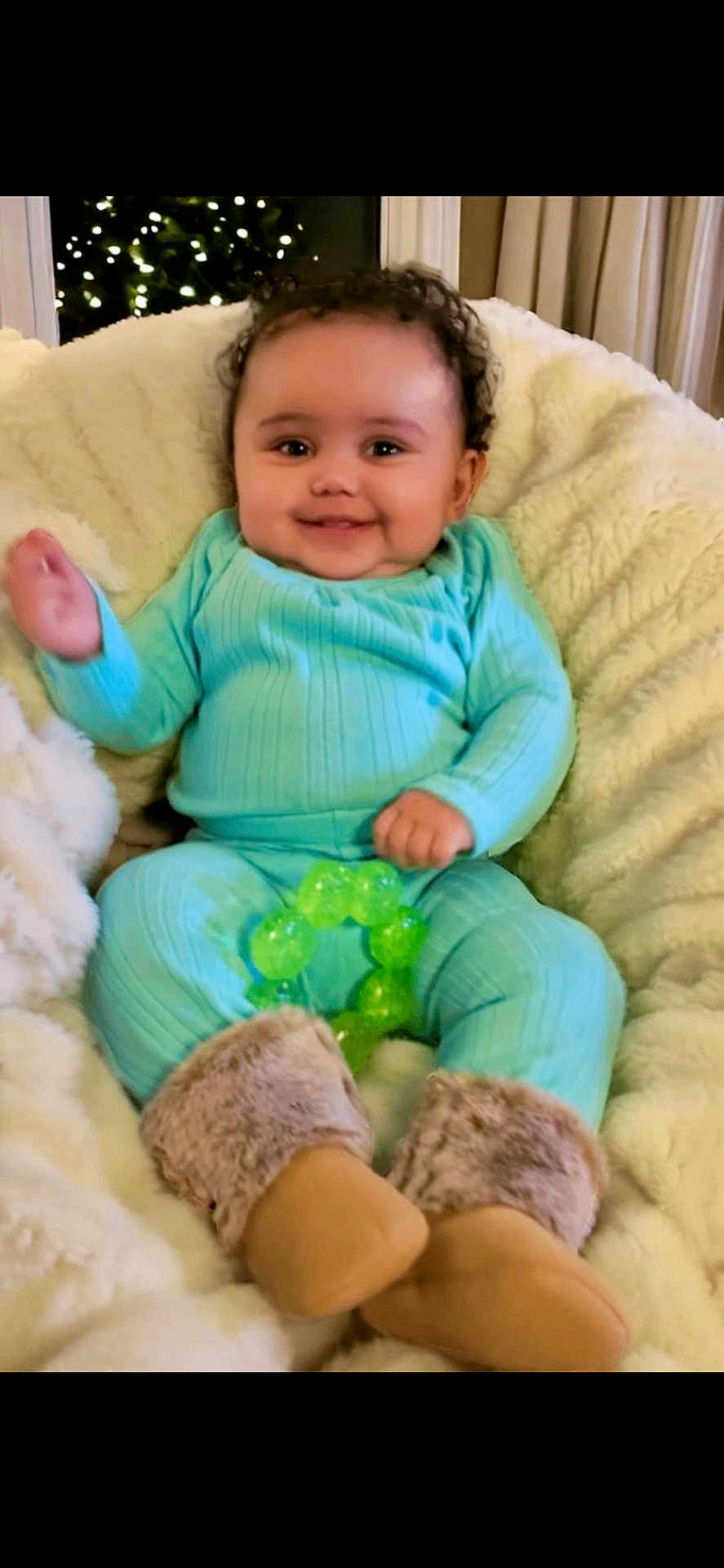 Cayla joined the competition — help win amazing prizes! baby, infant, smile, curly_hair, turquoise_clothing, fuzzy_boots, green_toy, blanket, cozy, indoors, happy, child, cute, soft_texture, portrait, sitting, warm, home, comfortable, teething_toy