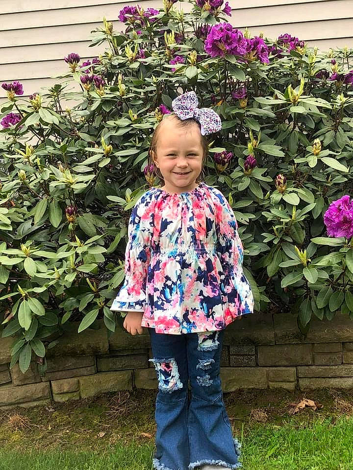 Kaelynn is registered to the contest to win money with this photo: annual_plant, baby_toddler_clothing, botany, flower, flowering_plant, grass, happy, head, joy, leaf, magenta, outerwear, pattern, person, petal, pink, plant, rose_family, shrub, sleeve