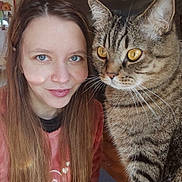 Tom a rejoint le concours — aidez-le/la à gagner de superbes lots ! woman, cat, tabby_cat, indoor, portrait, smile, long_hair, blue_eyes, golden_eyes, feline, pet, closeup, face, whiskers, casual_clothing, human, companion, animal, cozy, natural_light