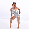 child, confident, dance, dancewear, expression, fashion, footwear, girl, hair_bun, leotard, performance, portrait, pose, silver, smile, studio, studio_lighting, tights, white_background, young