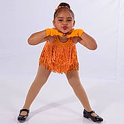Alura is registered to the contest to win money with this photo: black_shoes, child, dance_costume, fashion, fringe, girl, gloves, happy, orange, performance, playful, portrait, pose, pucker_lips, smile, standing, studio, tights, white_background, young
