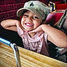 camo_cap, casual, child, cute, diner, girl, hand, happy, indoor, joyful, person, pink_shirt, portrait, posing, red_brick_wall, restaurant, seat, smile, table, wood