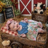 baby, child, infant, smiling, portrait, floral_dress, pink_bow, denim, wooden_wagon, rustic, farm, barn, plush_cow, chick, flowers, hay, blanket, outdoor, farmhouse, photography
