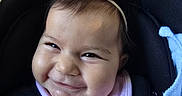 Nayla is registered to the contest to win money with this photo: baby, infant, child, smiling, happy, portrait, face, car_seat, sitting, headband, pink_bow, bib, blanket, clothing, close_up, indoors, vehicle, adorable, cheeks, photograph