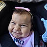 baby, infant, child, smiling, happy, portrait, face, car_seat, sitting, headband, pink_bow, bib, blanket, clothing, close_up, indoors, vehicle, adorable, cheeks, photograph