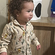 Saige is registered to the contest to win money with this photo: carpet, child, clothing, cozy, curly_hair, cute, expression, face, floor, furniture, heater, home, indoor, pajamas, person, sleepwear, standing, toddler, wooden_cabinet, young_child