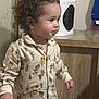 carpet, child, clothing, cozy, curly_hair, cute, expression, face, floor, furniture, heater, home, indoor, pajamas, person, sleepwear, standing, toddler, wooden_cabinet, young_child