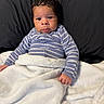 Milo is registered to the contest to win money with this photo: baby, infant, blanket, striped_clothing, onesie, bed, pillow, cozy, indoors, portrait, face, cute, child, young, sleepwear, resting, comfort, soft_texture, newborn, curious