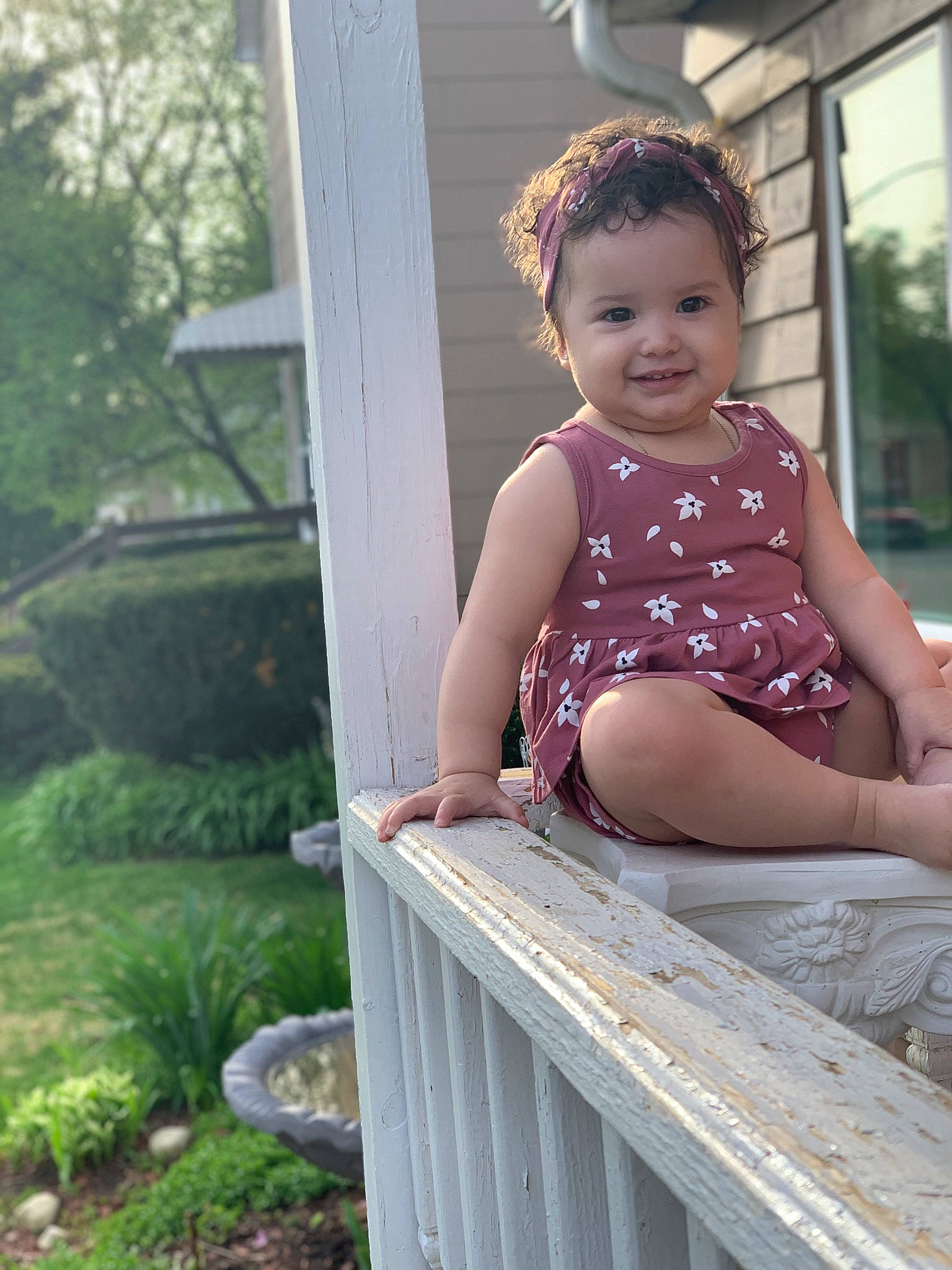 Jaylani is registered to the contest to win money with this photo: baby_toddler_clothing, chin, dress, eye, fun, grass, happy, human_leg, joy, leisure, magenta, pattern, person, plant, sitting, skin, smile, thigh, toddler, tree