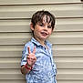 background, beige_wall, blue_shirt, boy, casual_clothing, child, expression, floral_pattern, happy, outdoor, peace_sign, person, portrait, posing, smile, standing, summer, wet_hair, wristband, young