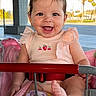 baby, child, smiling, shopping_cart, blanket, pink, outdoor, daylight, happy, person, clothing, earrings, foot, seatbelt, metal, grid_floor, trees, architecture, sunlight, cute