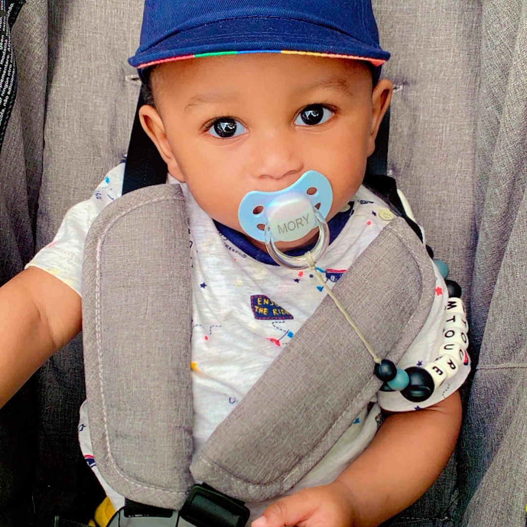 Mory participe au concours pour gagner de l'argent avec cette photo : baby, baseballcap, bodypart, bonnet, cap, clothing, couch, face, finger, furniture, hand, hat, head, homedecor, pants, person, photography, portrait, sitting, toy