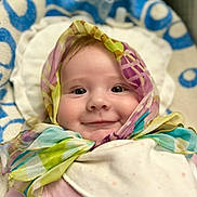 Alexa is registered to the contest to win money with this photo: baby, child, face, smile, scarf, colorful, portrait, closeup, infant, pink_clothing, blanket, soft, cute, happy, indoors, headwear, wrapped, cheeks, eyes, person