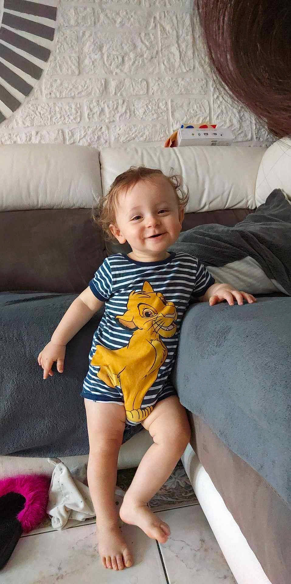 Lilio a rejoint le concours — aidez-le/la à gagner de superbes lots ! baby_toddler_clothing, barefoot, comfort, couch, finger, fun, happy, human_leg, joy, knee, lap, leg, living_room, person, sitting, skin, smile, t_shirt, textile, thigh
