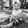 Emmie joined the competition — help win amazing prizes! toddler, child, smile, grass, outdoor, headband, bow, happy, sitting, nature, black_and_white, portrait, curly_hair, sunlight, trees, cute, baby, legs, feet, clothing