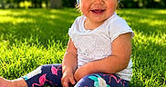 Emmie is registered to the contest to win money with this photo: child, toddler, smiling, grass, outdoor, sunlight, headband, blue, bow, legs, feet, leggings, flamingo, pattern, white_shirt, happy, nature, summer, greenery, portrait