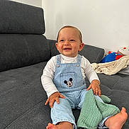 Wyssem a rejoint le concours — aidez-le/la à gagner de superbes lots ! toddler, child, smiling, sitting, indoor, couch, overalls, mickey_mouse, clothing, barefoot, blanket, toy, happy, face, person, home, casual, light, cozy, cute