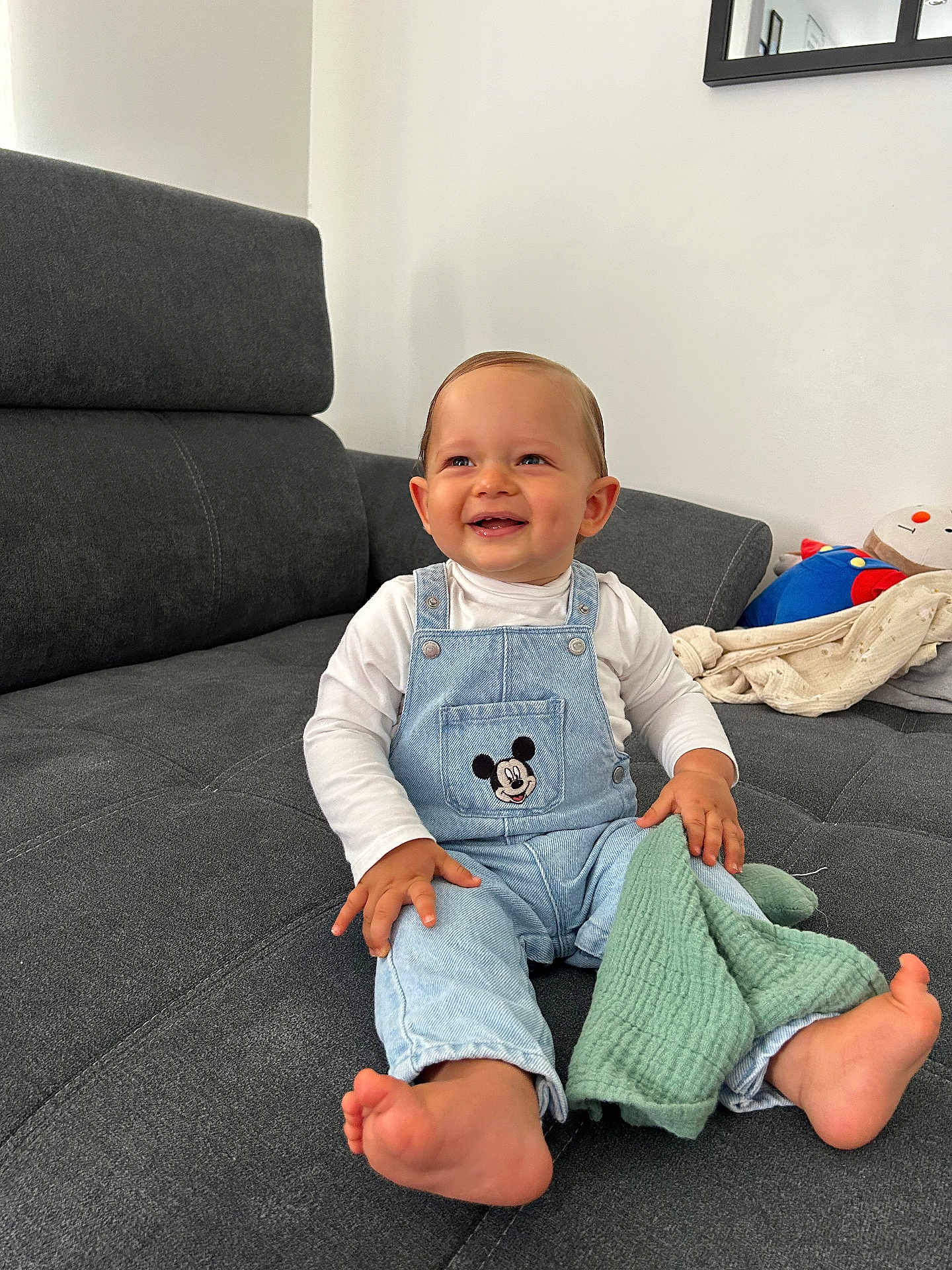 Wyssem a rejoint le concours — aidez-le/la à gagner de superbes lots ! toddler, child, smiling, sitting, indoor, couch, overalls, mickey_mouse, clothing, barefoot, blanket, toy, happy, face, person, home, casual, light, cozy, cute