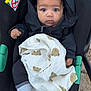 baby, child, stroller, blanket, teddy_bear_pattern, jacket, black_clothing, socks, cute, wide_eyes, infant, outdoor, person, seat, comfort, expression, bundle, portrait, young_child, baby_carrier