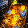Jacob is registered to the contest to win money with this photo: baby, infant, basket, string_lights, yellow_clothing, glowing_lights, snow, window, cozy, winter, indoor, cute, child, warm_lighting, decorative_lights, portrait, holiday, smiling, festive, soft_texture