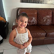 Kaya joined the competition — help win amazing prizes! child, girl, smile, happy, standing, indoor, living_room, couch, leather_couch, wall_art, tile_floor, clothing, hair_tie, person, portrait, casual, home, furniture, young_child, cute